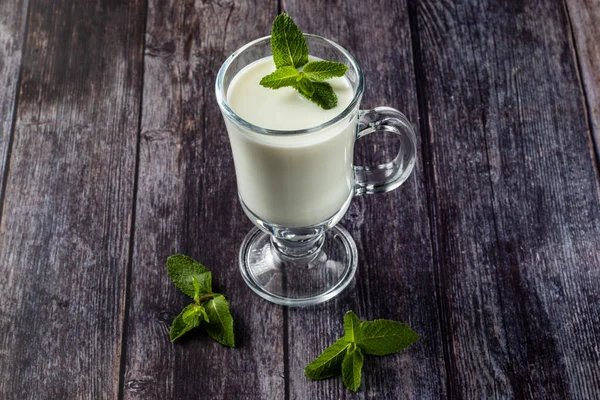 Ayran en un vaso, bebida de leche agria, yogur, decorado con una hoja de menta. Sobre un fondo de madera —  Fotos de Stock