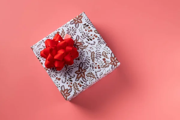 Bayram için pembe arka planda kırmızı kurdeleli hediye kutusu. Boşluğu kopyala — Stok fotoğraf