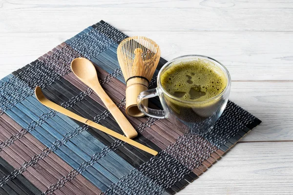 Bevanda di tè matcha verde e accessori su uno sfondo di legno bianco. Concetto cerimonia del tè giapponese . — Foto Stock