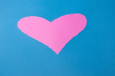 Kağıt üzerinde kalp şeklinde delik, mavi arka planda pembe.