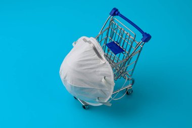 Tıbbi maske izolasyonu. Solunum yollarının virüslere, gribe ve koronavirüse karşı korunması. COVID-19. Alışveriş konsepti, mavi arkaplan.