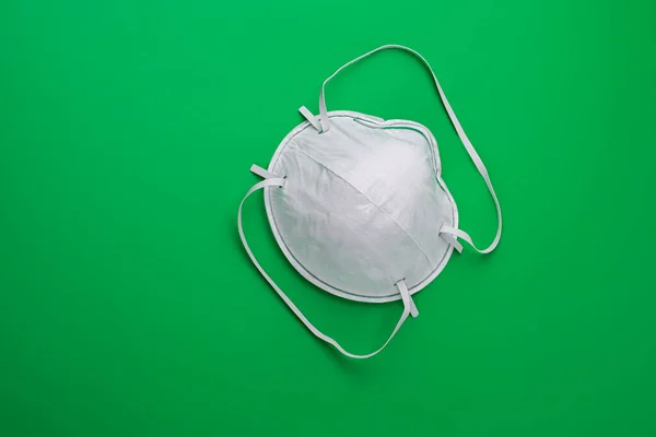 Medical mask isolation. Protection for respiratory tracts against viruses, influenza and coronavirus. Health care and surgical concept. Green background. — Stock Photo, Image