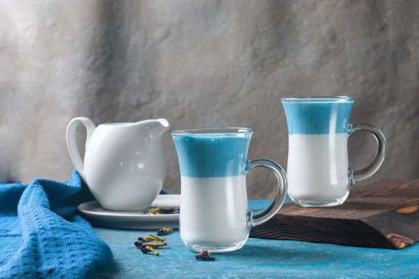 2 tazas de café con leche azul matcha, bebida de crema de mariposas de guisante sobre un fondo azul —  Fotos de Stock