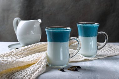 Dalgona Matcha Blue Latte, açık gri arka planda cam bir fincanda kibrit kremi. Yatay yönelim