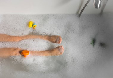 Küvette banyo yapan bir çocuğun bacakları ve ayakları.