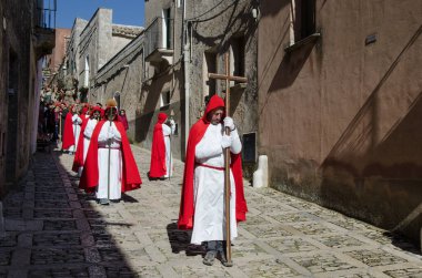 Erice, SIcily, İtalya Mart 2014 - Erice, Sicilya, İtalya 'nın Gizemleri geçit töreni sırasında bir an. Kırmızı pelerinli ve kapüşonlu bir adam bir haç taşıyor.