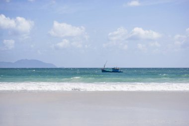 Gök mavisi bir arka planda deniz dalgaları olan gökteki Vietnamlı balıkçı teknesi. Doktor Let plajı