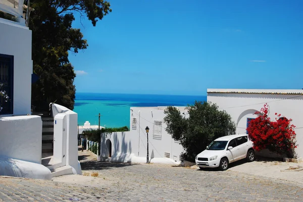 Tunus 'ta yaz aylarında güneşli havada Sidi Bou Said' de mavi deniz ve sokak manzarası