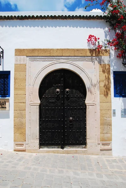 Geleneksel Tunus siyah metal kapısı. Beyaz bir duvarda taş bantlı bir deseni var. Sidi Bou Said, Tunus