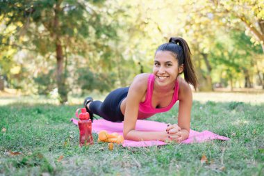 Parlak tebessümlü bir kadın parkta kalas sallıyor.