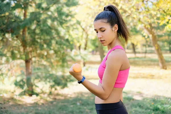 Fit girl trains biceps avec haltères orange — Photo