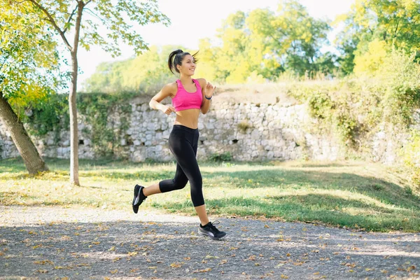 Sport fille est en cours d'exécution dans le parc et sourire — Photo