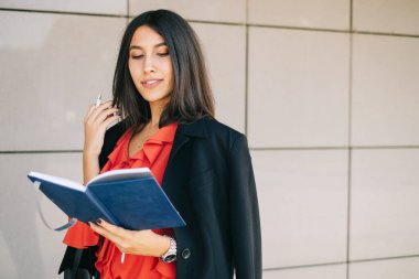 Defter okuyan ve saçlarına dokunan bir kadın.