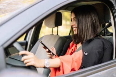 Şık bir kadın araba kullanırken sohbet ediyor.