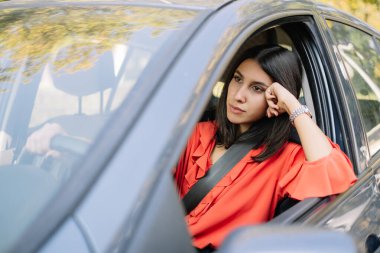 Bir kadın arabada otururken düşünür