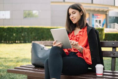 tablet ile bir bankta oturmuş işkadını