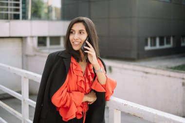 Genç iş kadını cep telefonuyla konuşurken iyi görünüyor.