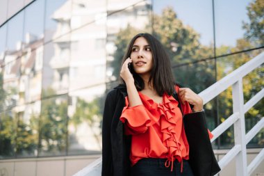 Dışarıdaki kadın ofis çalışanı telefon görüşmeleri yapıyor.