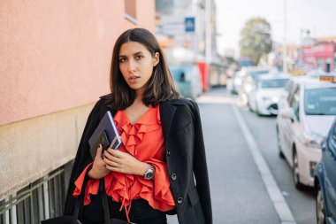 Kürklü kadın kaldırımda oturuyor.