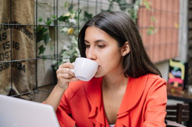 Kafede kahve içen turuncu bluzlu kız.
