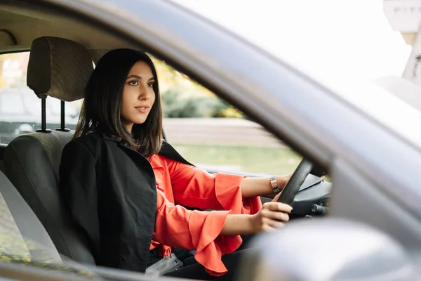 Wonderful young woman driving a grey car