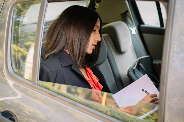 Business woman writing on backseat of a car