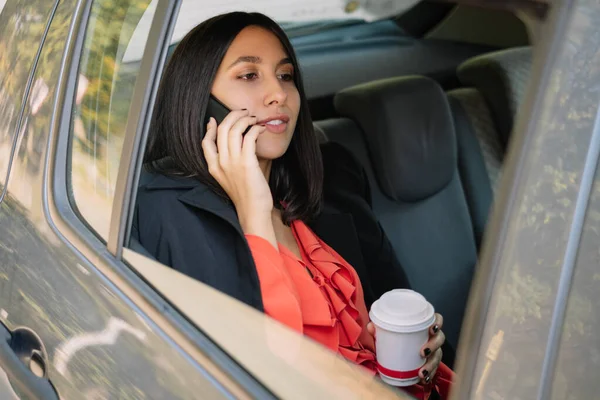 Confident woman with coffee talking on her mobile