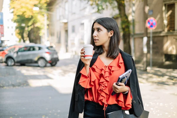 Женщина пьет кофе во время прогулки по улице — стоковое фото