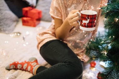 Geyik desenli kupalarla yerde oturan kız.