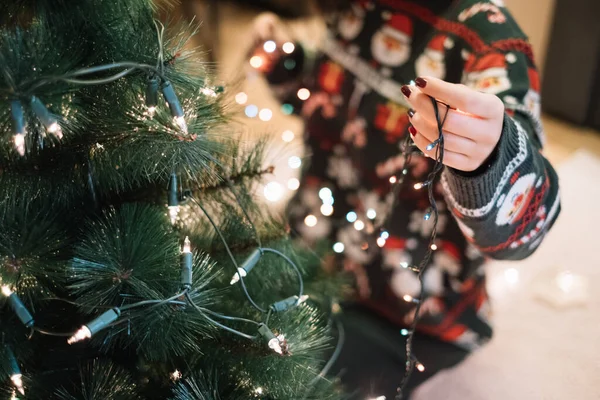 Kızlar Noel ışıklarını ağaca asıyor.