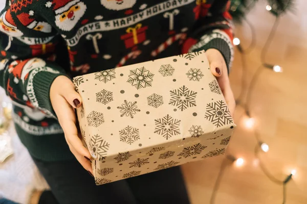 Ragazza seduta sul pavimento e con in mano la confezione regalo di Natale — Foto Stock