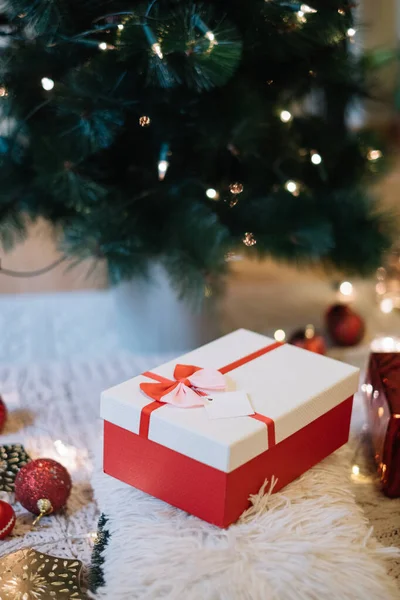 Bílá a červená zdobená dárková krabice pod vánoční stromeček — Stock fotografie