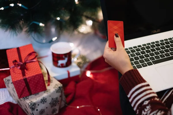 Meninas mão segurando cartão na frente do laptop — Fotografia de Stock