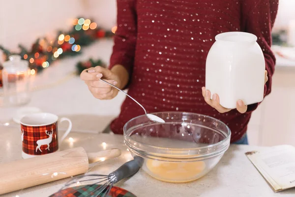Девушка наливает ложку с сахаром в миску с взбитыми яйцами — стоковое фото