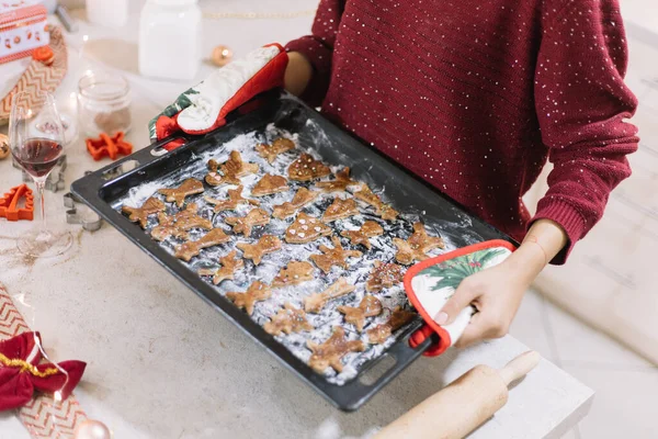 Großaufnahme von Frauenhänden, die ein Blech mit Weihnachtskeksen zum Backen bereit halten. — Stockfoto