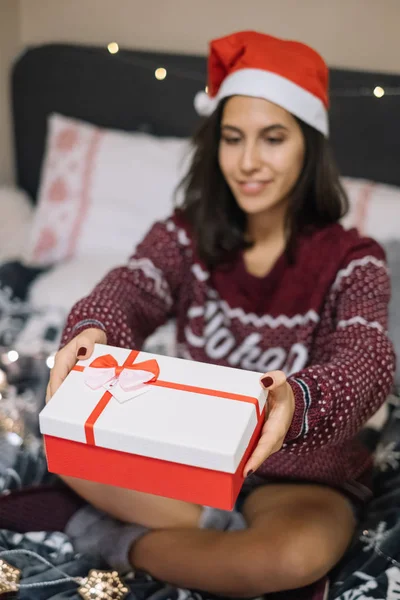 Pretty girl giving Christmas present in bedroom