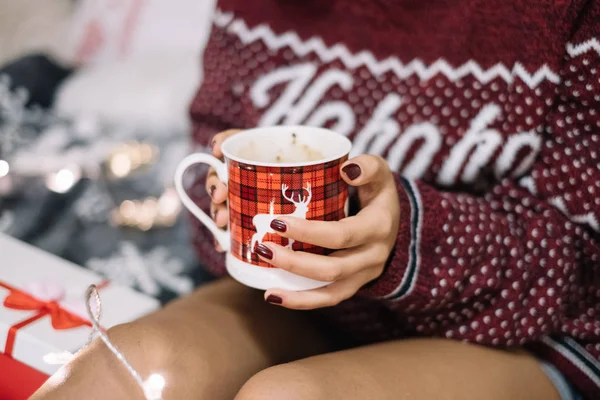 Girl holding coffee mug over her legs