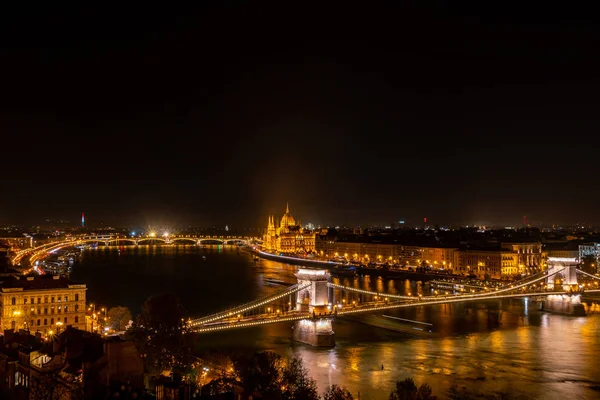 Budapesti éjszakai táj, kilátás a hidakra és a Parlament épületére. — Stock Fotó