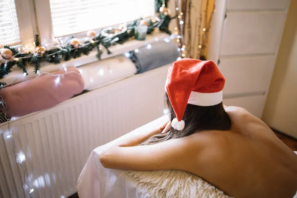 Kobieta z kapeluszem Mikołaja leżącego na łóżku masażu — Zdjęcie stockowe