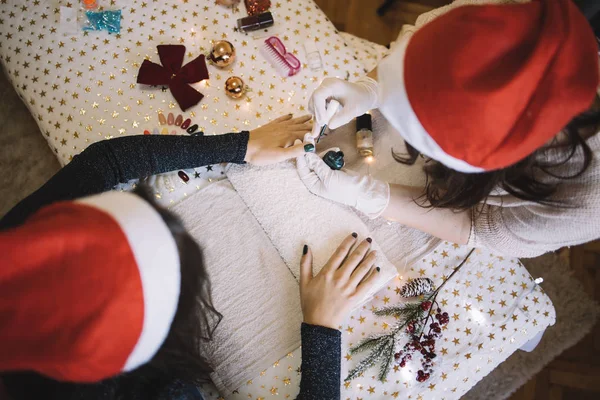Manikiurzystka z kapeluszem Mikołaja robi świąteczny manicure — Zdjęcie stockowe