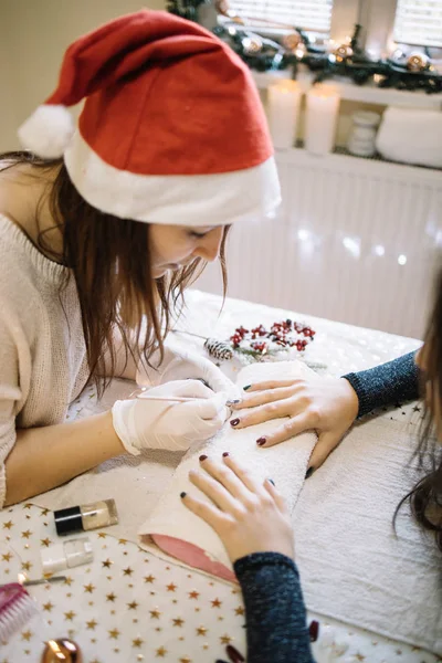 Manicura con sombrero de Santa haciendo manicura y pintando clavos —  Fotos de Stock