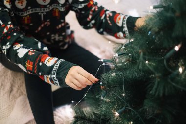 Kırpılmış kadın Noel ağacını ışıklarla süslüyor.