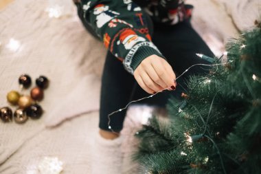 Kız elleri Noel ışıklarını bir ağaca ekliyor