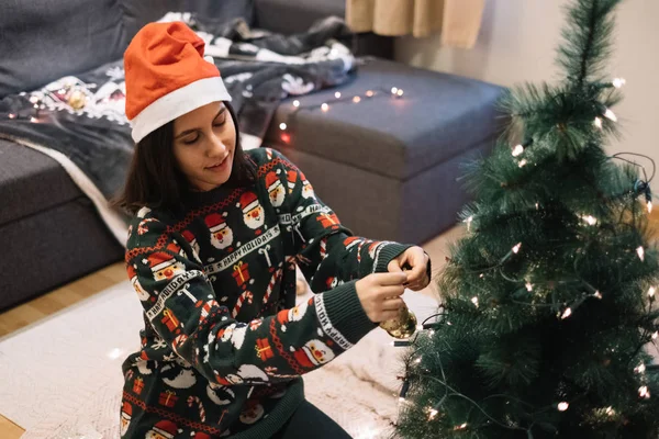 Woman decorating a Christmas tree with balls