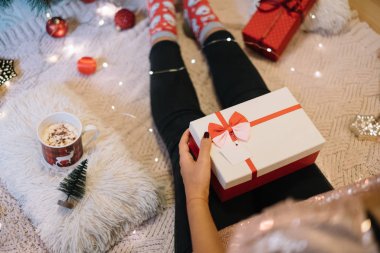 Kırpılmış kadın kucağında hediyesiyle yerde oturuyor.