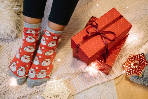 Womans legs with Santa socks on knitted blanket