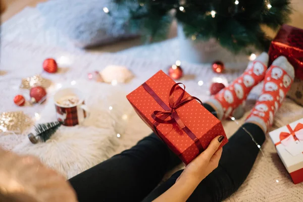 Femmina mano tenendo regalo di Natale accanto all'albero — Foto Stock