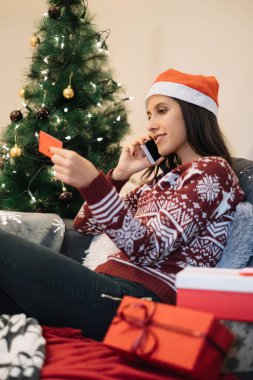 Kanepede oturan kız, evden hediyeler sipariş ediyor.