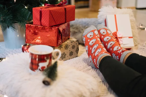Female legs next to presents under Christmas tree