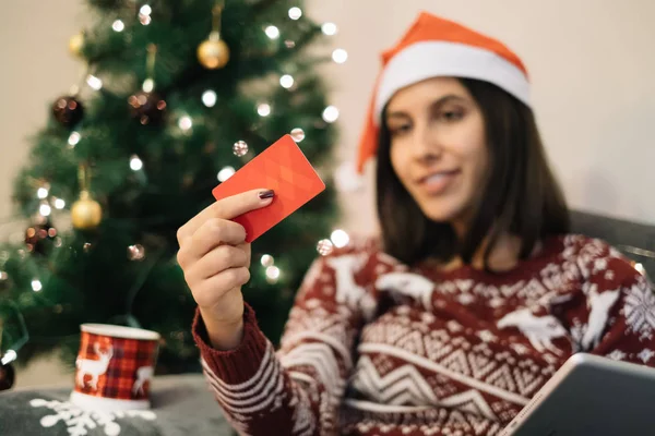 Out of focus Christmas tree and girl holding in focus red card